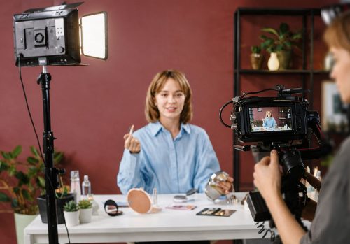 Woman being filmed about her products seen through a camera lens.