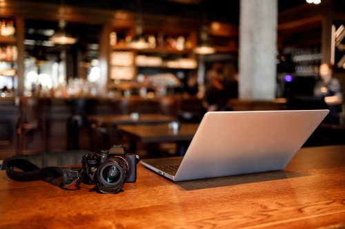Professional camera and laptop on a table in a restaurant.