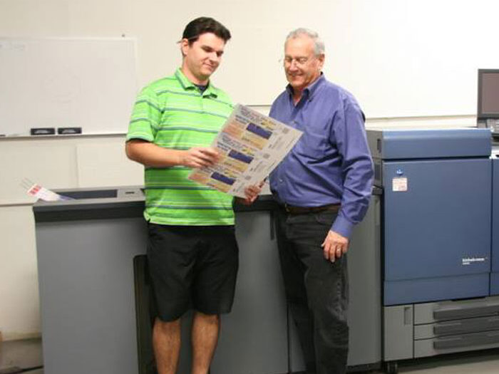 Troy and Loren Ford standing in front of a printing machine
