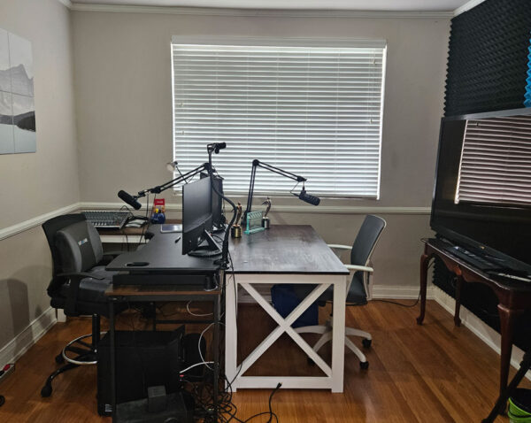 Recording studio with tables, chairs, computers, monitors, and microphones.